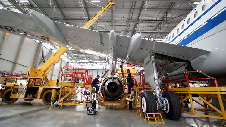 Der große Moment: Mit einem mobilen Kran hängen Flugzeugbauer einer A320 das Triebwerk unter die Tragfläche.