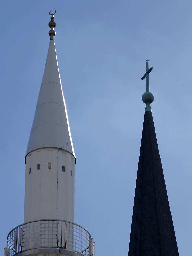 Die Spitze des Minarett der Yavus Sultan Selim Moschee (l.) mit dem Halbmond und das Kreuz auf der Kirchturmspitze der Liebfrauenkirche in Mannheim.