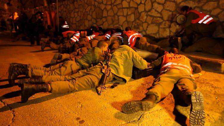 Israelische Soldaten schützen sich bei einem Raketenangriff auf die israelische Stadt Kirjat Mal'achi.