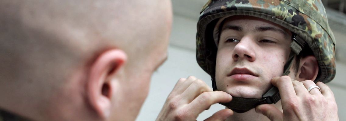 Ein Bundeswehrsoldat hilft einem Kameraden den Helm aufzusetzen (Archivfoto).