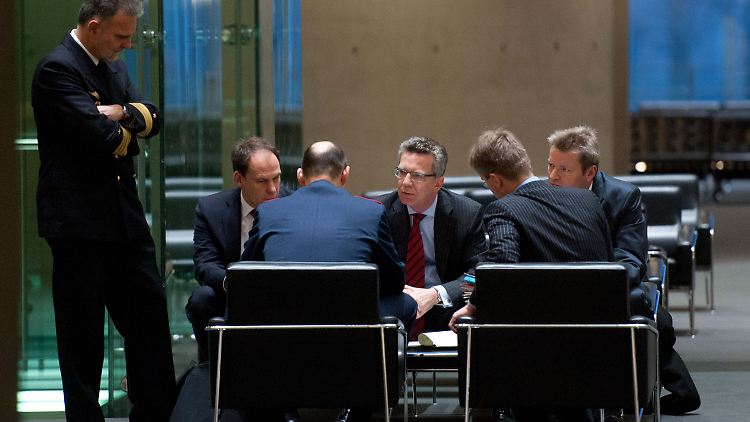 De Maizière berät sich mit seinen Mitarbeitern.