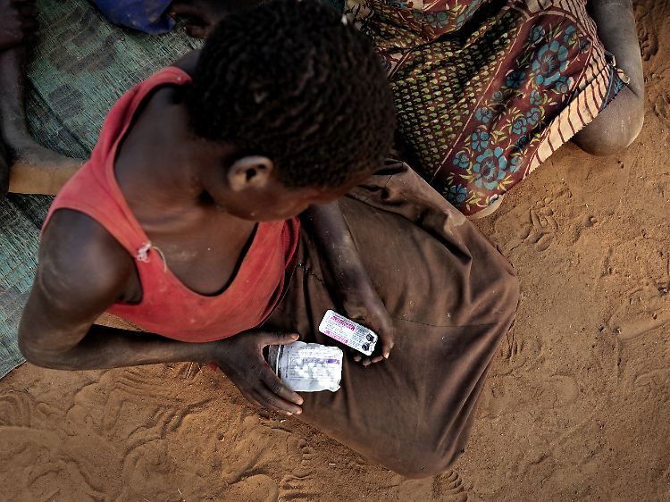 Alice Amito sitzt mit Epilepsie-Tabletten in den Händen vor einer Hütte im Kitgum Distrikt in Norduganda. Sie leidet am Kopfnicken-Syndrom.