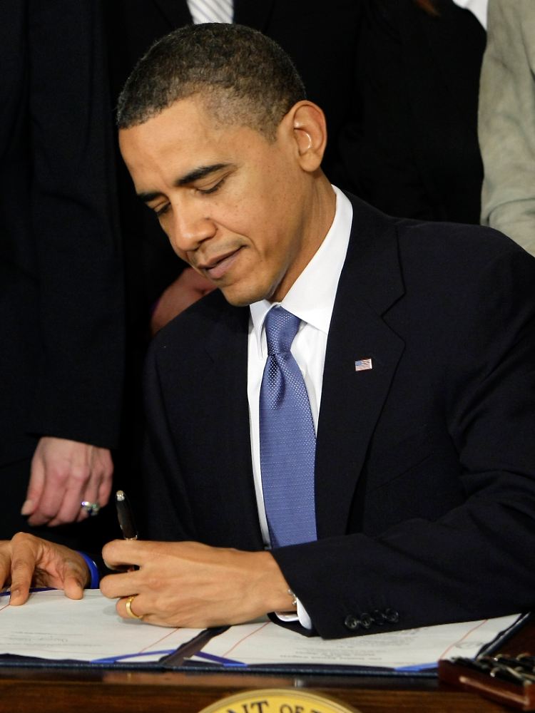 Mit links: Obama setzt seine Unterschrift unter die historische Reform.