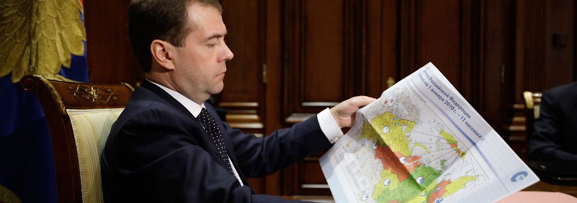 Medwedew hält eine Karte mit den russischen Zeitzonen in den Händen.