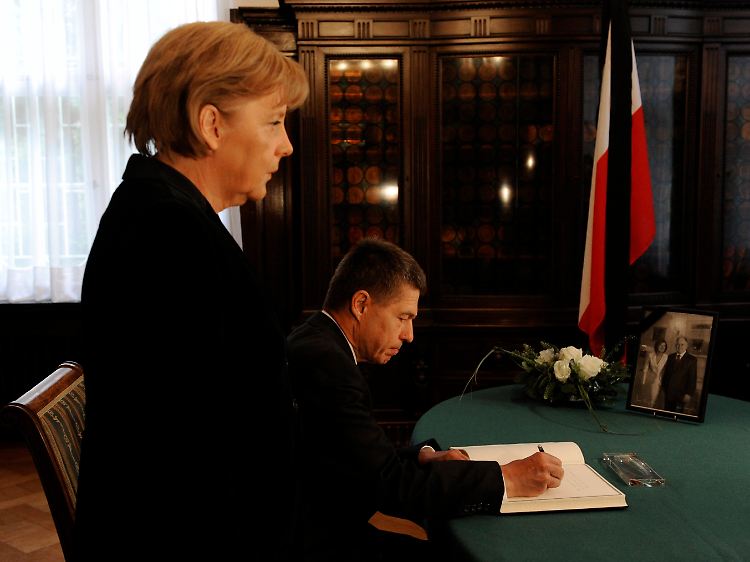Kanzlerin Merkel und ihr Ehemann tragen sich in das Kondolenzbuch der polnischen Botschaft in Berlin ein.