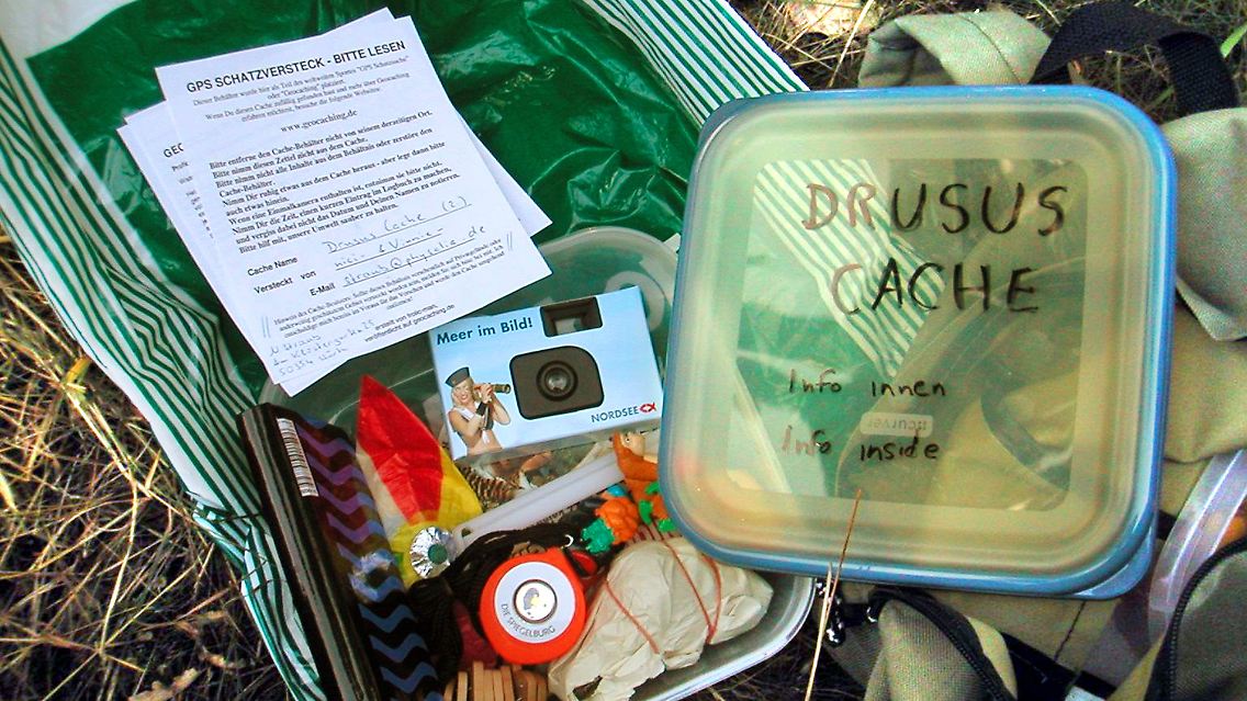 Logbuch, Info-Blätter, Einwegkamera im "Cache" (zu Deutsch: "Versteck") - mit dem Fotoapparat lichten sich Schatzjäger ab, um ihren Erfolg zu dokumentieren.