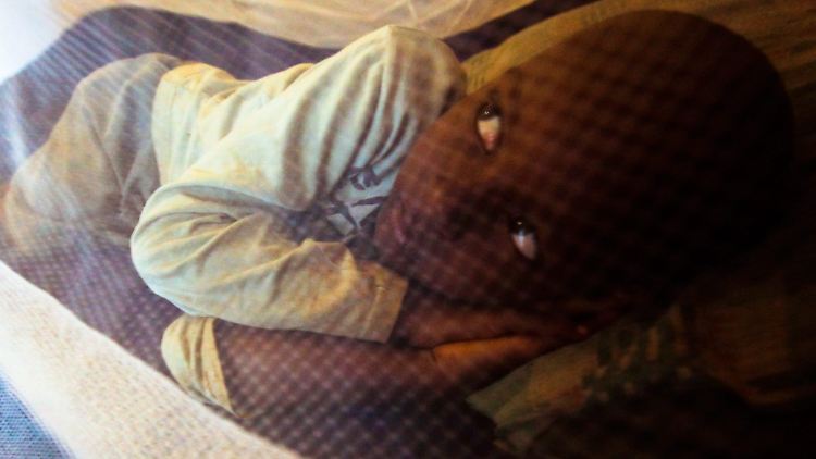 Ein fünfjähriges Kind liegt in einem Slum der kenianischen Hauptstadt Nairobi unter einem Moskitonetz.