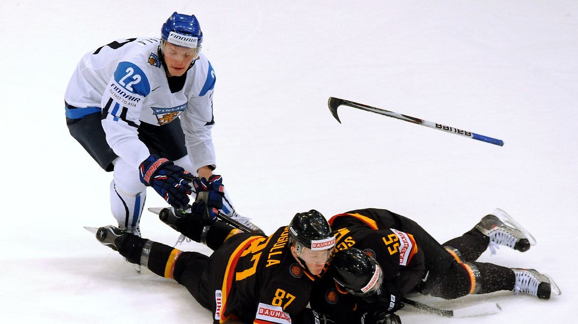 Die Deutschen Philip Gogulla (M) und Felix Schütz (r) liegen am Boden während der Finne Tommi Santala nach dem Puck stochert.