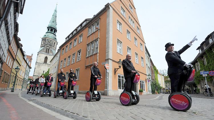 Der Vorstandschef der Stadtwerke Hannover, Feist (2.v.r.), und Schauspiel-Intendant Walburg (3.v.r.) testen in der Innenstadt von Hannover eine Stadtführung auf Elektro-Rollern.