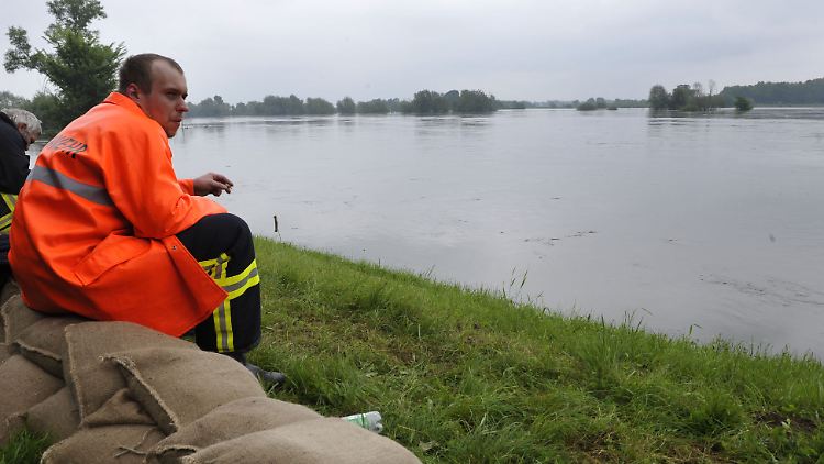 Ein Feuerwehrmann macht nahe Neuzelle eine Pause beim Verstärken der Deiche.