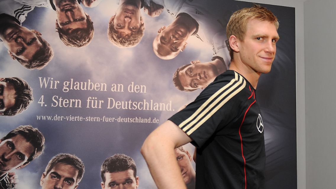 Abwehrchef Per Mertesacker vor einem Werbeplakat.
