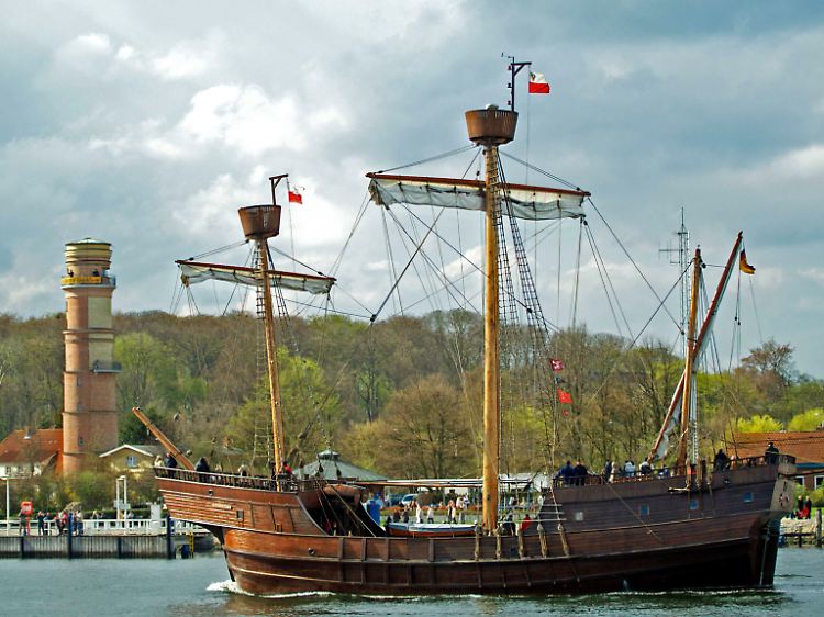 Einfahrt in den Hafen: Der Nachbau eines Hanseschiffes aus dem 15. Jahrhundert passiert den Leuchtturm von Travemünde.