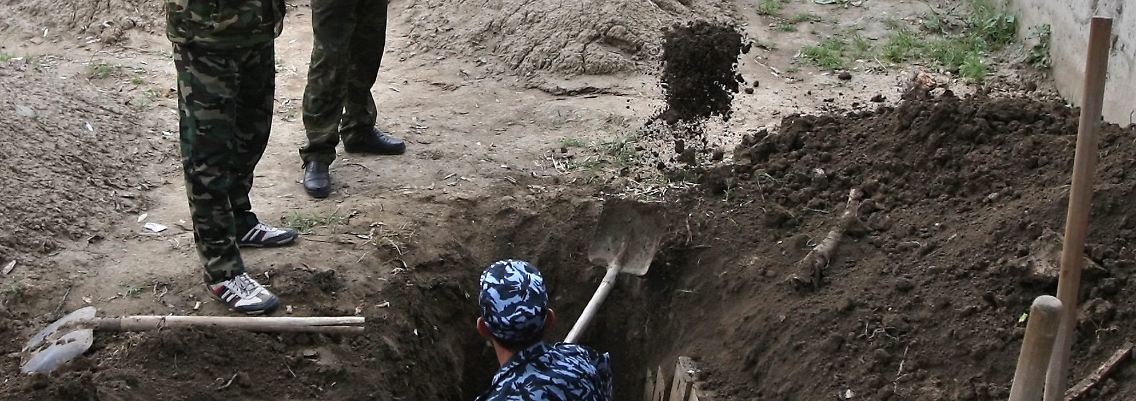 Kirgisische Polizisten schaufeln Gräber auf dem Friedhof in Osh.