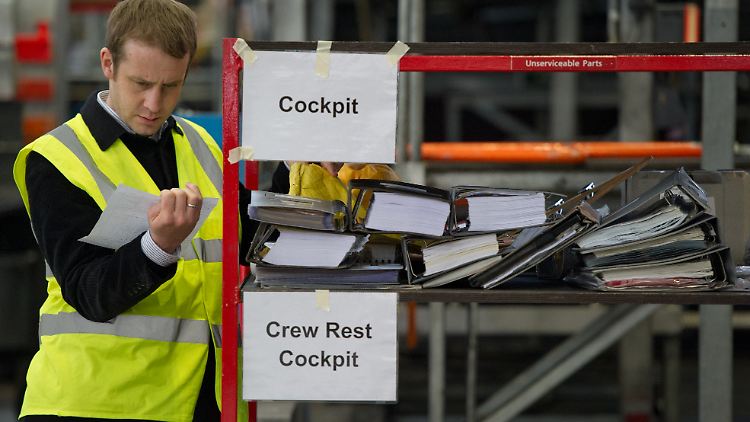 Ein Helfer katalogisiert auf dem Flughafen Frankfurt am Main schwere Bordhandbücher aus dem Cockpit eines Airbus.