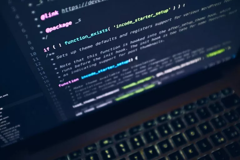 Auf einem Laptop sind verschiedene Zeilen Code zu sehen. Wir zeigen dir Wege, eine Fotografen Website zu erstellen.