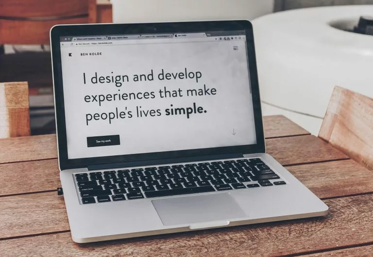 Blick auf einen aufgeklappten Laptop auf einem Holztisch. Wir zeigen dir Schritt für Schritt, wie du eine Portfolio Website erstellen kannst!