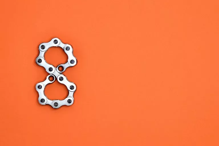 Eine aus Ketten geformte acht liegt auf einem orangefarbenem Hintergrund. Wir zeigen dir in unserem Website Baukasten Vergleich die Top 8 Anbieter!