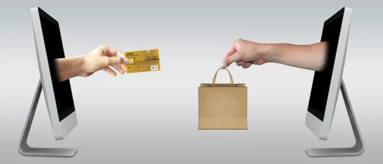 Es gibt zwei Bildschirme und aus jedem kommt eine Hand heraus. Die Hände tauschen eine Papiertüte gegen eine Kreditkarte aus
