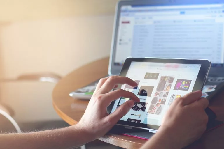 Die Finger klicken auf den Bildschirm eines Tablets, um etwas online zu tun